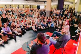 Panel talk on a stage: several people sit and speak while a large crowd watches closely.