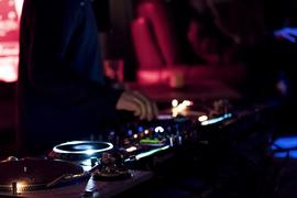 Eine Person bedient ein DJ-Pult im Dunkeln.