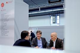 Drei Männer unterhalten sich am ILC Stand