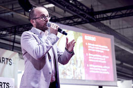 A man with a microphone speaks on a stage.