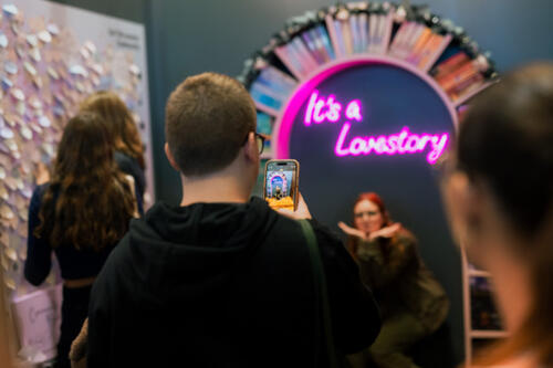 Ein Besucher fotografiert eine Besucherin, die unter der Leuchtschrift "It's a Lovestory" posiert. 