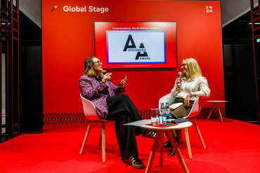 Panel talk on the Global Stage at the Frankfurt Book Fair: two women in conversation in front of the Aficionado Award logo.