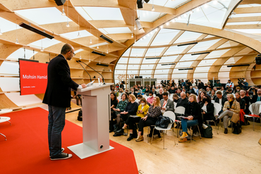 Mann redet auf der Bühne im Pavillon