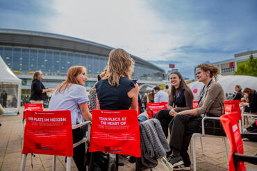 Besucher*innen sitzen in einem Stuhlkreis auf dem Freigelände der Frankfurter Buchmesse