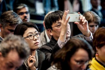 An asian man in a crowd shoots photos