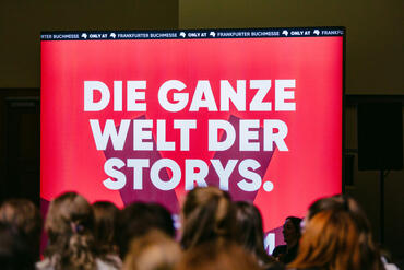Leuchtreklame im Buchmesse-Design mit der Aufschrift "Die ganze Welt der Storys".