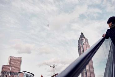 A man drives up an escalator, in the background you can see the Frankfurt trade fair tower