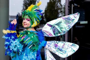 Girl wears peacock costume and smiles into the camera