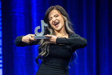 Gewinnerin des TikTok Book Awards hält die Trophäe in den Händen und freut sich. 