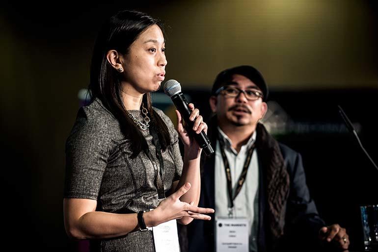 a woman stands on stage and gives a speach