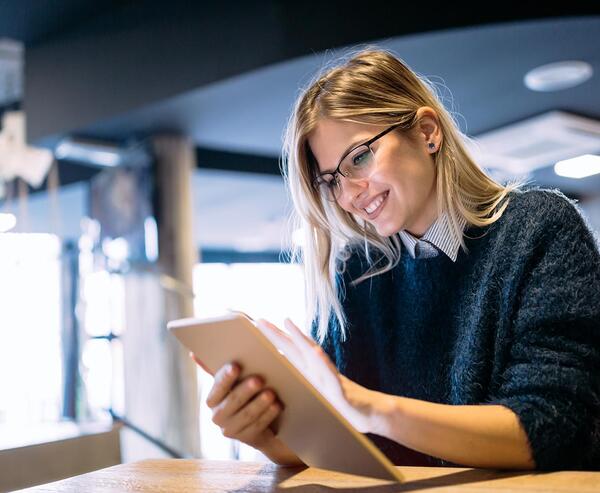 A woman with a content facial expression is using a tablet.