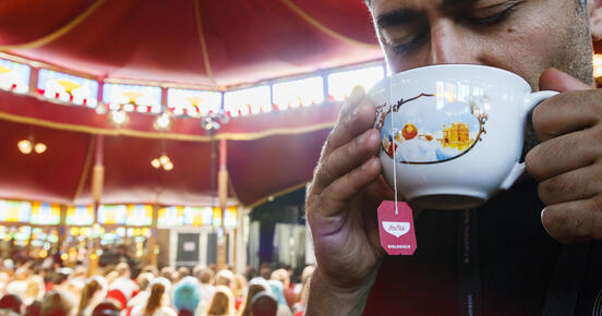 Mann trinkt Tee aus einer Tasse aus der ein YogiTee-Beutel hängt. 