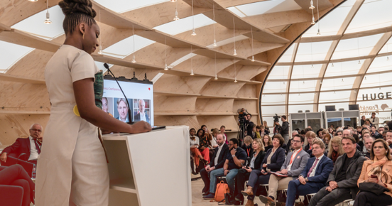 Frau redet auf Bühne im Pavillon