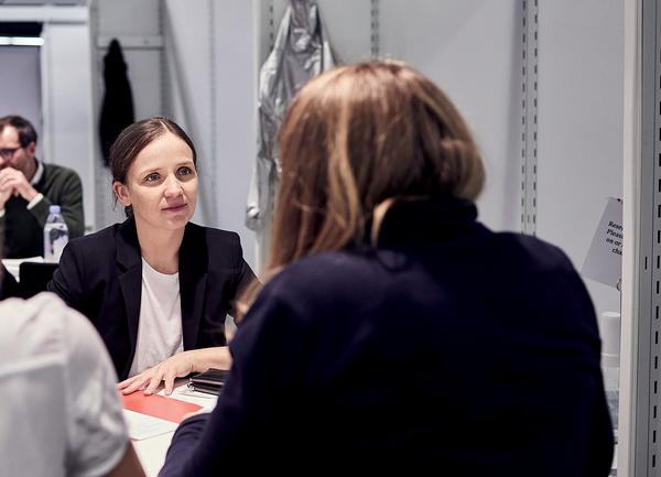 Woman sits in Publishers Rights Corner and listens to a dealer