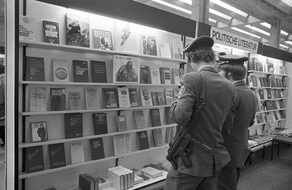 Two police officers providing security at the Soviet stand have a look at their offer for political literature