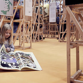 Girl sits on the ground and reads in her illustrated book