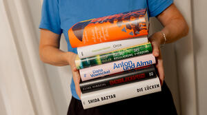 Eine Person hält einen Stapel mit den Büchern der Shortlist für den Deutschen Buchpreis 2026