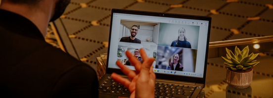 Person joins a video call on a laptop; four participants appear in a grid on the screen.