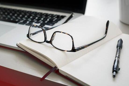 Laptop, Brille und Notizbuch