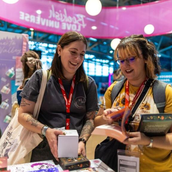 Zwei Besucherinnen freuen sich über Bücher und Goodies auf der Frankfurter Buchmesse.
