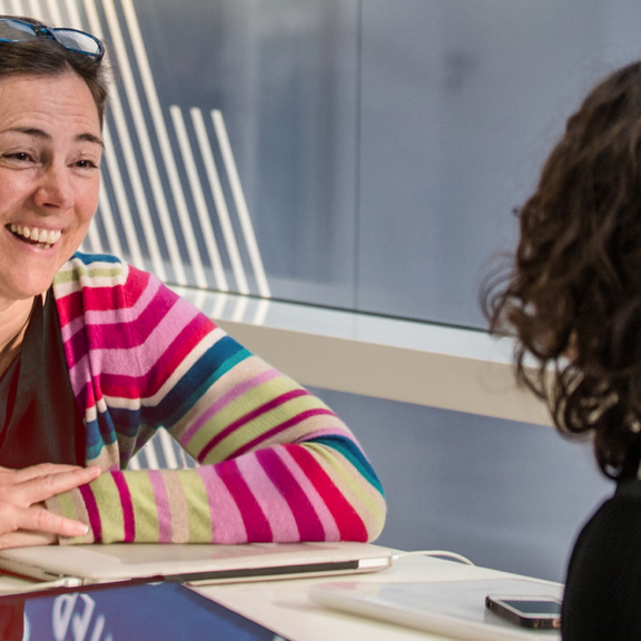 Frau sitzt an einem Tisch und lächelt