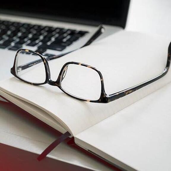Laptop, Brille und Notizbuch