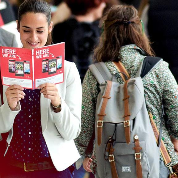 Eine Frau läuft über die Messe und liest in der Messe Zeitschrift