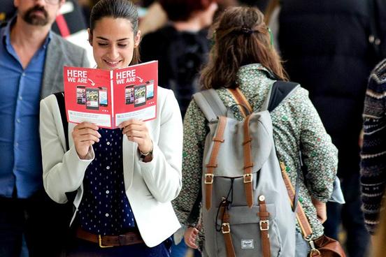 Eine Frau läuft über die Messe und liest in der Messe Zeitschrift