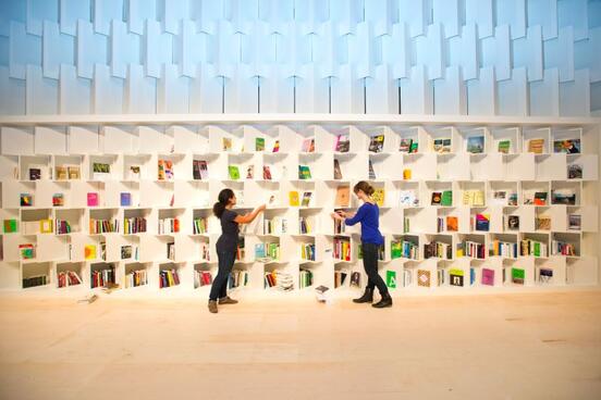 Aussteller, die Bücher in ein großes Bücherregal stellen. 