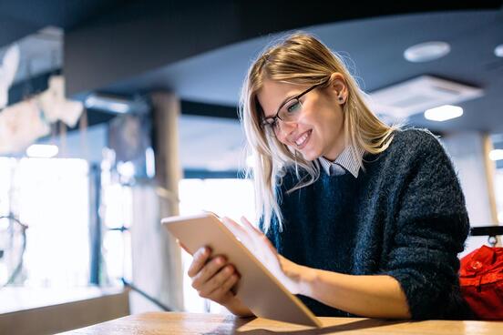 A woman with a content facial expression is using a tablet.