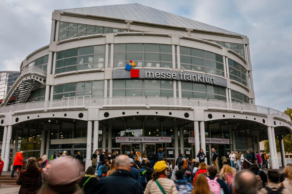 Eingang zur Frankfurter Buchmesse mit Menschen die dorthin strömen.