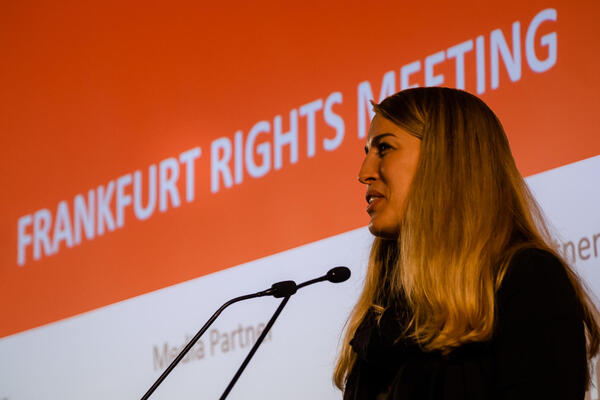 Sprecherin steht vor zwei Mikrofonen. 