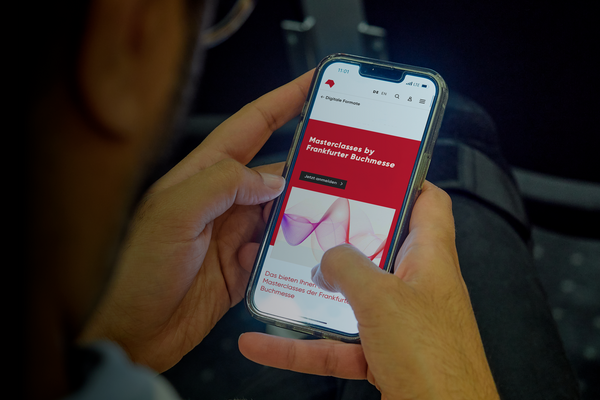 A person is holding a smartphone in their hands with the masterclasses website open.