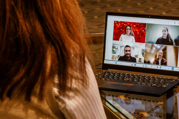 Ein Laptop auf dem ein Meeting stattfindet steht auf einem Tisch. Man sieht die Teilnehmer des Meetings auf dem Bildschirm.
