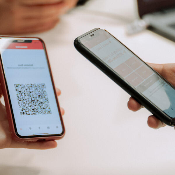 A mobile device is scanning an online ticket code on another mobile device.