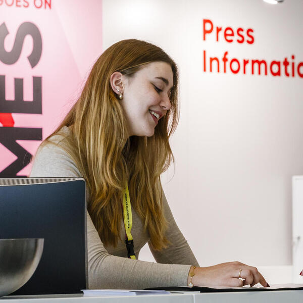 Staff and media representative talk at the info desk at Frankfurter Buchmesse's Press Centre 